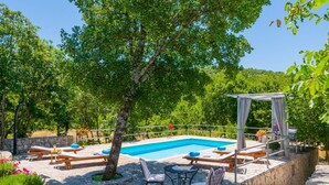 A poolside area with lounge chairs, a pergola, and a small table with chairs. - Ognjistar in Zmijavci (Zmijavci)