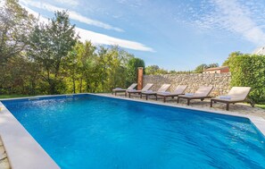 Une piscine avec des chaises longues et un mur en pierre.