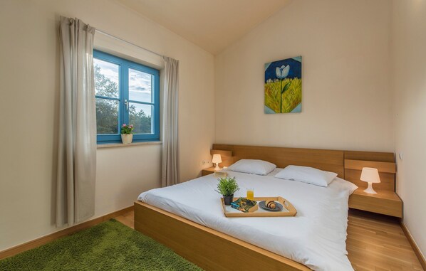 Un lit bien fait, avec un plateau contenant des articles pour le petit-déjeuner, une lampe de chevet et une fenêtre avec des rideaux.