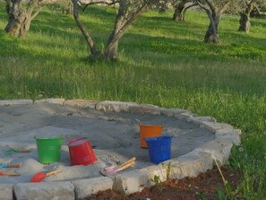 A garden area with a concrete border, various colored buckets, and gardening tools. - Christall in Kastelir (Kastelir-Labinci)