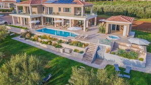 Una casa moderna de dos pisos amb piscina, zona d'estar a l'exterior i panells solars.