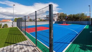 An outdoor basketball court with a fence, green artificial turf, and a blue playing surface. - M5 in Vir With 2 Bedrooms and 2 Bathrooms (Vir)