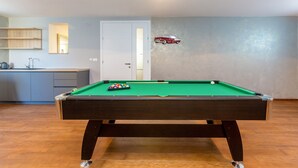 A pool table with a green felt surface, a red car decal on the wall, and a kitchen area with a sink and cabinets in the background. - Roko in Malinska With 4 Bedrooms and 2 Bathrooms (Malinska-Dubasnica)