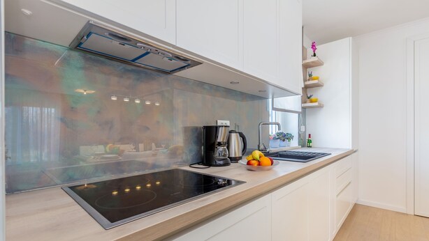 A modern kitchen with a black induction cooktop, white cabinets, and a wooden countertop. - Roko in Malinska With 4 Bedrooms and 2 Bathrooms (Malinska-Dubasnica)