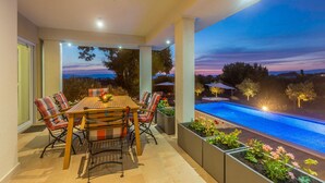 A patio with a pool, outdoor furniture, and a view of the landscape. - Roko in Malinska With 4 Bedrooms and 2 Bathrooms (Malinska-Dubasnica)