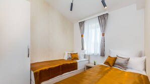 A hotel room with two single beds, a small bedside table, a window with curtains, and a light fixture. - Roko in Malinska With 4 Bedrooms and 2 Bathrooms (Malinska-Dubasnica)