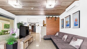 A modern living room with a wooden ceiling, a grey sofa, a TV, and a plant. - Fantasia in Barban With 4 Bedrooms and 2 Bathrooms (Marcana)