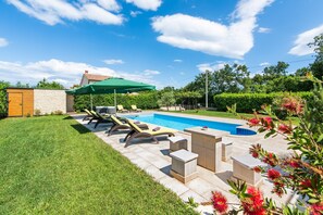 A backyard with a swimming pool, lounge chairs, and a green umbrella. - Fantasia in Barban With 4 Bedrooms and 2 Bathrooms (Marcana)