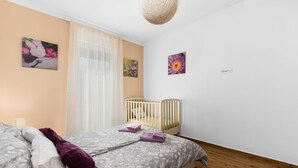 A bedroom with a bed, a crib, and wall art. - Fantasia in Barban With 4 Bedrooms and 2 Bathrooms (Marcana)
