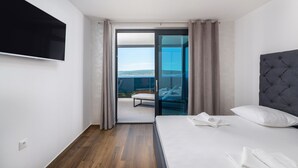 A modern hotel room with a bed, a flat-screen TV, and a balcony with a view. - Twins III in Crikvenica (Crikvenica)