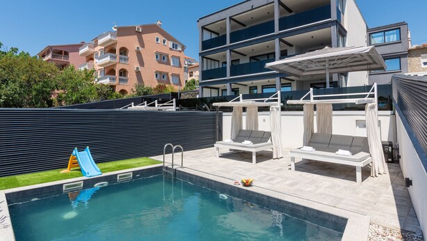 A swimming pool with a slide, lounge chairs, and a covered seating area. - Twins III in Crikvenica (Crikvenica)