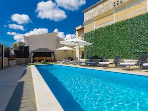 A swimming pool with lounge chairs and umbrellas, a stone wall, and a barbecue area. - Patrick in Pazin With 4 Bedrooms and 4 Bathrooms (Pazin)