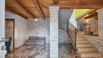 A spacious room with a stone wall, a wooden ceiling, and a marble floor.