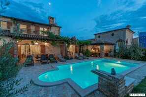 A poolside area with a stone pool, lounge chairs, and a stone building with a tiled roof. - Bella Vista in Barat (Visnjan)