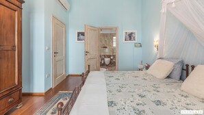 Ein Schlafzimmer mit Bett, Kleiderschrank, einem durchgegangenen Tür erkennbaren Badezimmer und einem Nachttisch mit Lampe.