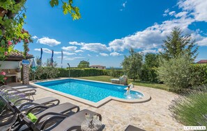 A swimming pool with lounge chairs and a swan statue, surrounded by greenery and a clear sky. - Bella Vista in Barat (Visnjan)