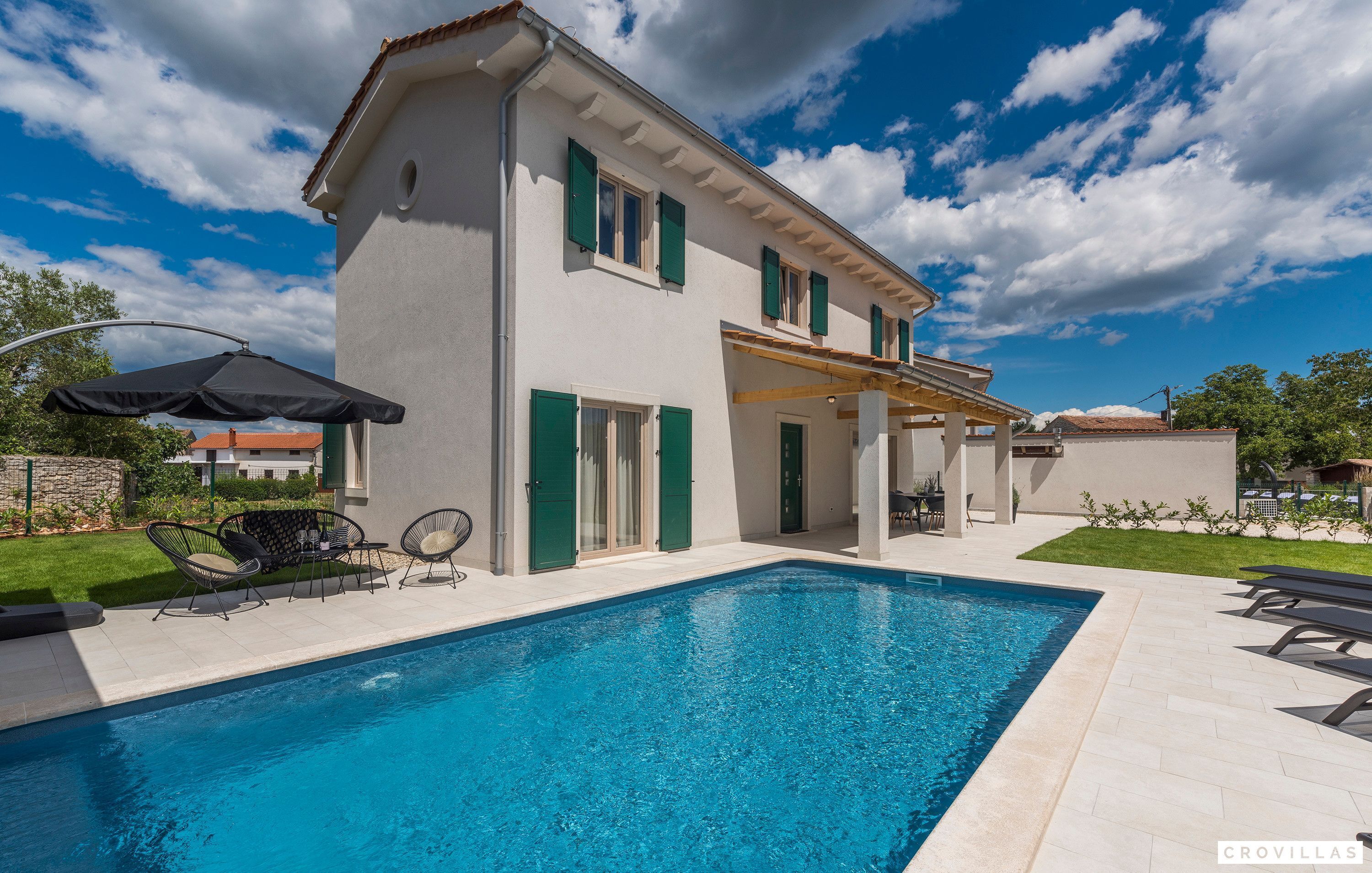 A two-story house with a swimming pool, outdoor furniture, and a pergola.