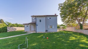 A two-story house with a stone wall, a grassy yard, and a tree. - Seconda in Rojni i With 3 Bedrooms and 3 Bathrooms (Barban)