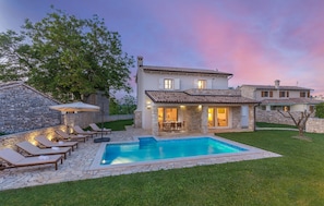 Une maison avec une piscine, des murs en pierre et un jardin.