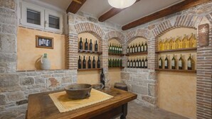 A rustic cellar with stone walls, wooden beams, and shelves of wine bottles. - Lipa in Krnica With 4 Bedrooms and 3 Bathrooms (Marcana)