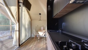 Une cuisine de taille réduite, dotée d’un plan de travail en bois, d’une cuisinière encastrée et d’une fenêtre avec des rideaux.