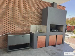 An outdoor kitchen with a brick wall backdrop, a sink, and a grill. - Grande Arche in Li Njan (Liznjan)