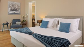 A neatly made bed with a blue throw, a chair, a small table with a plant, and a painting on the wall. - Vigneto in Brtonigla (Brtonigla)