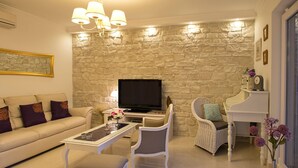 Una sala de estar con una pared de piedra, un sofá, una mesa de centro, un televisor y un piano.