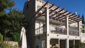 Un edificio de dos pisos con balcón, pérgola y antena parabólica.