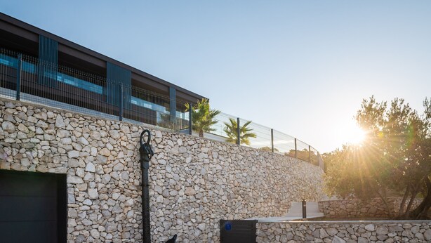 A modern building with a stone wall and an anchor sculpture. - Panoramica in Koroma no (Rasa)