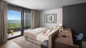 A modern hotel room with a large bed, a wooden desk, and a view of a green landscape through a sliding door. - Panoramica in Koroma no (Rasa)