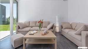 A modern living room with a beige sofa set, a wooden coffee table, and a vase with flowers. - Complex Teca in Go an Draguzeti (Barban)