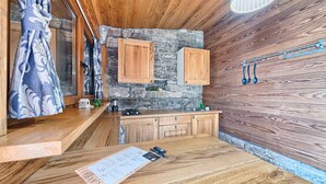 A compact kitchen with wooden cabinets, a stone wall, and a small window with curtains. - Stone in Murter With 1 Bedrooms and 1 Bathrooms (Tisno)