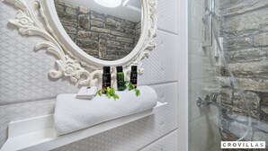 A bathroom with a stone wall, a white vanity, a large ornate mirror, and a shower area. - Stone in Murter With 1 Bedrooms and 1 Bathrooms (Tisno)