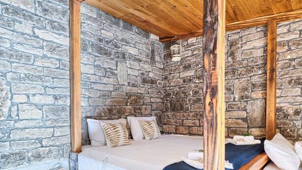 A rustic bedroom with a stone wall, a wooden four-poster bed, and a small wooden nightstand. - Stone in Murter With 1 Bedrooms and 1 Bathrooms (Tisno)