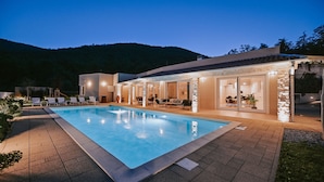 A swimming pool with a patio area, outdoor seating, and a view of a hilly landscape. - Natura III in Veprinac (Opatija)