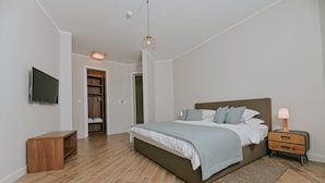 A bedroom with a bed, bedside table, TV, wardrobe, and a hanging light fixture. - Natura III in Veprinac (Opatija)