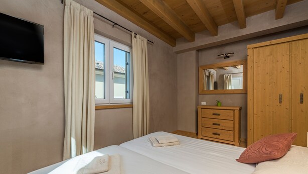 A bedroom with a bed, a wooden wardrobe, a dresser, a mirror, and a window with curtains. - Chiara in Premantura (Medulin)