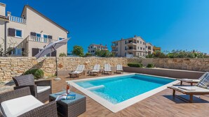A swimming pool with lounge chairs and a stone wall. - Chiara in Premantura (Medulin)