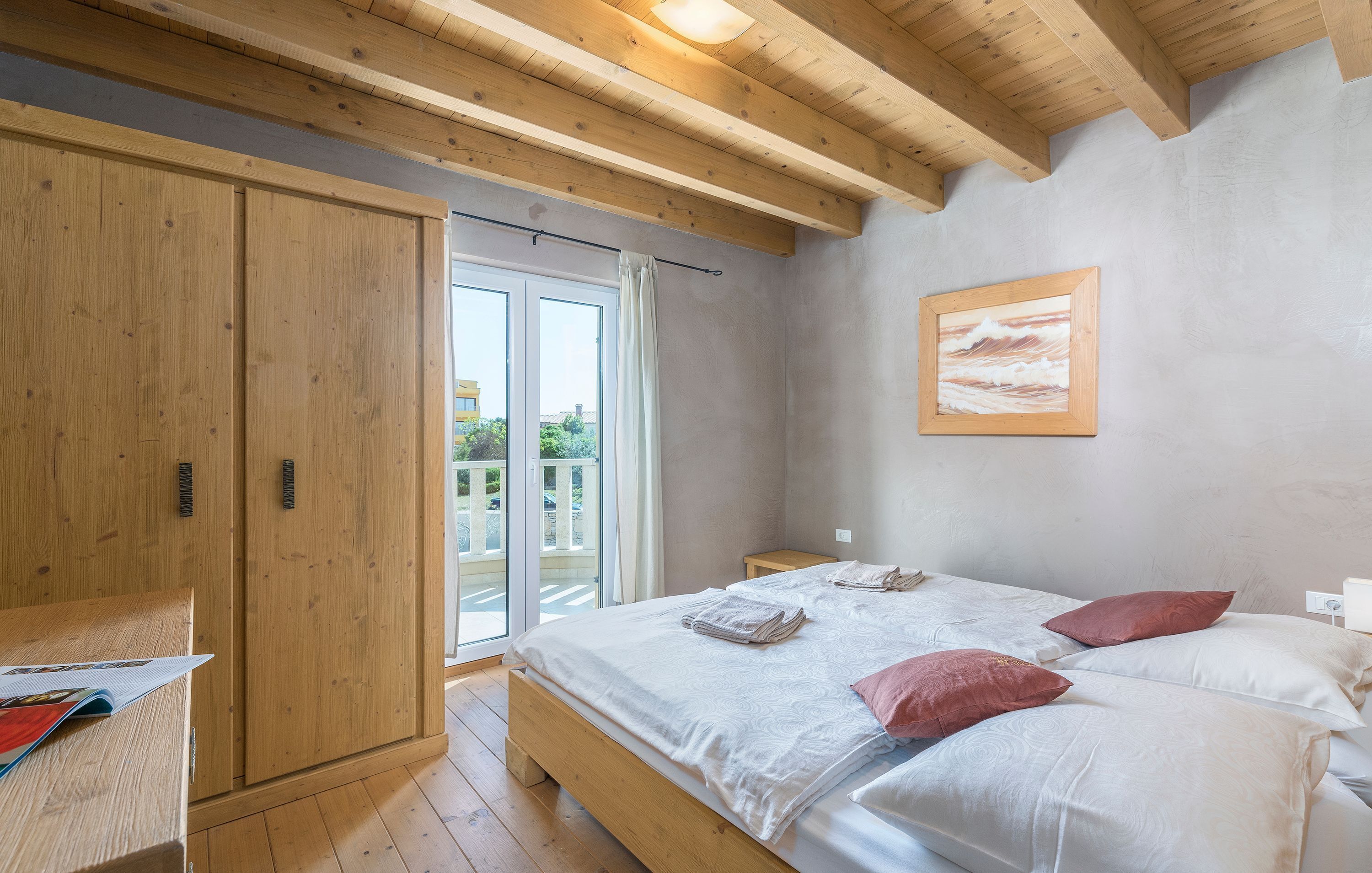 Un dormitorio con cama de madera, mesita de noche, armario y puerta corrediza de vidrio al exterior.