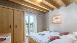 A bedroom with a wooden bed, a nightstand, a wardrobe, and a sliding glass door to the outside. - Chiara in Premantura (Medulin)