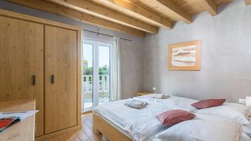 Un dormitorio con cama de madera, mesita de noche, armario y puerta corrediza de vidrio al exterior.