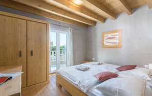 A bedroom with a wooden bed, a nightstand, a wardrobe, and a sliding glass door to the outside. - Chiara in Premantura (Medulin)