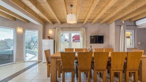 A dining area with a wooden table and chairs, a ceiling fan, and a television on the wall. - Chiara in Premantura (Medulin)