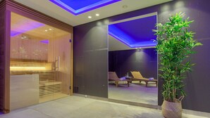 Ein moderner Spa-Raum mit einer Holzsauna, einem Massagetisch und einer großen Topfpflanze.