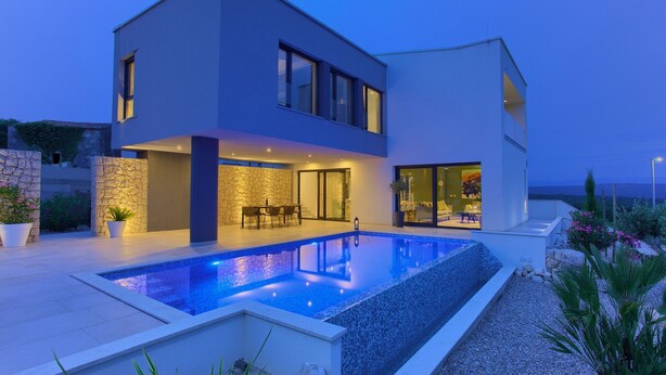 Ein modernes, zweistöckiges Haus mit Schwimmbad, Steinmauern und einer Terrassenfläche.