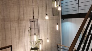 A modern interior with exposed concrete walls, hanging light fixtures with plants, and a wooden staircase. - Grande Barbara in Vi Inada (Vizinada)
