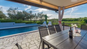 A covered outdoor area with a pool, chairs, and a table with a bottle and flowers. - Pendolina in Buje With 3 Bedrooms and 1 Bathrooms (Buje)