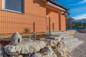 A building with a stone facade, a small stone structure resembling a chimney, and a set of stone steps leading to a covered entrance. - Pendolina in Buje With 3 Bedrooms and 1 Bathrooms (Buje)