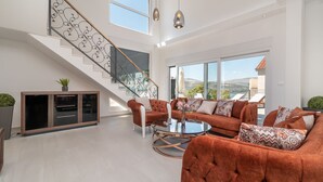 A spacious living area with a staircase, large windows, and a modern sofa set. - Sun Stone in Trogir With 4 Bedrooms and 4 Bathrooms (Trogir)